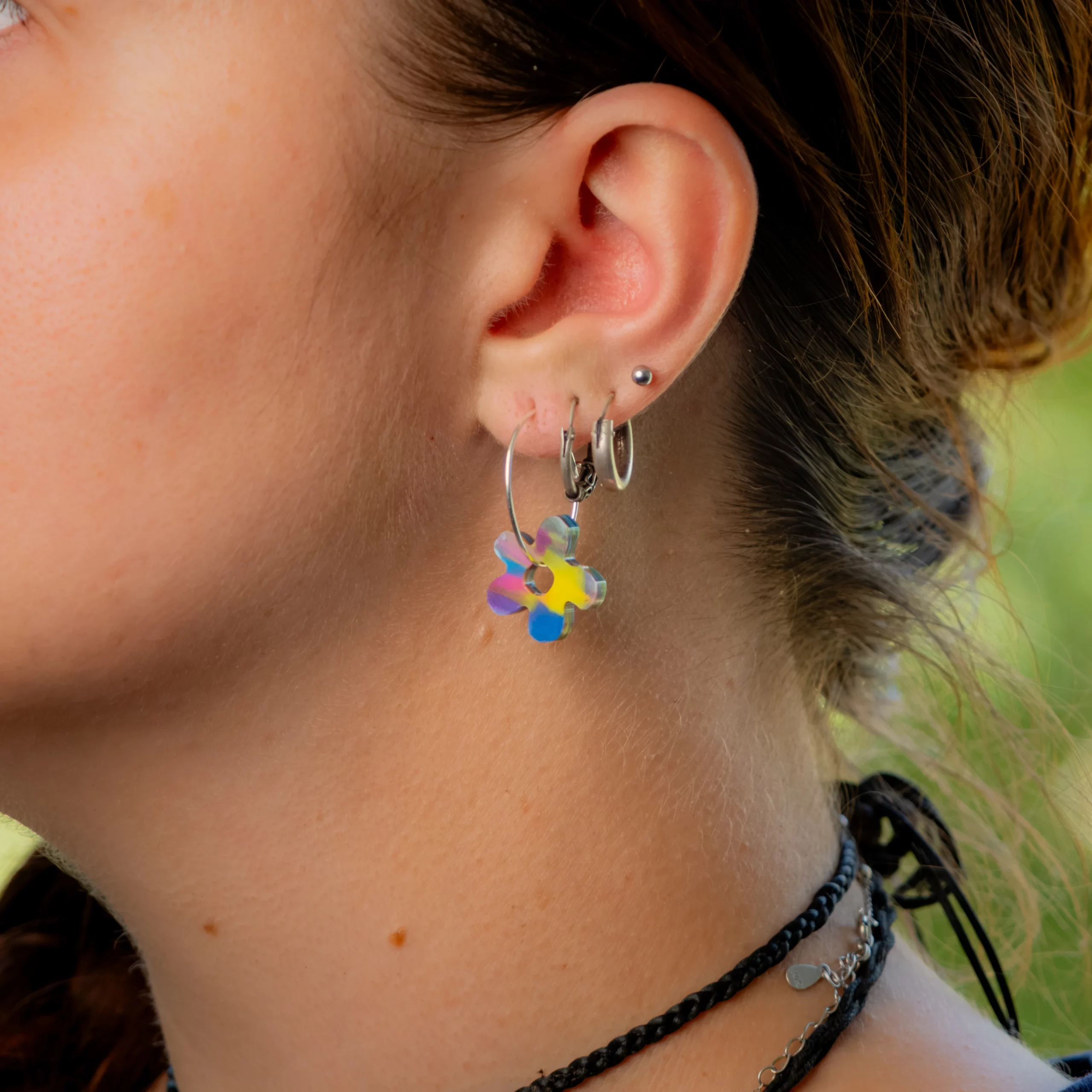 Femme portant la boucle d'oreille recyclée Fleur de Sauvage Méditerranée, collection Les Beaux Jours, coloris Bleu Jaune Violet/Rose.