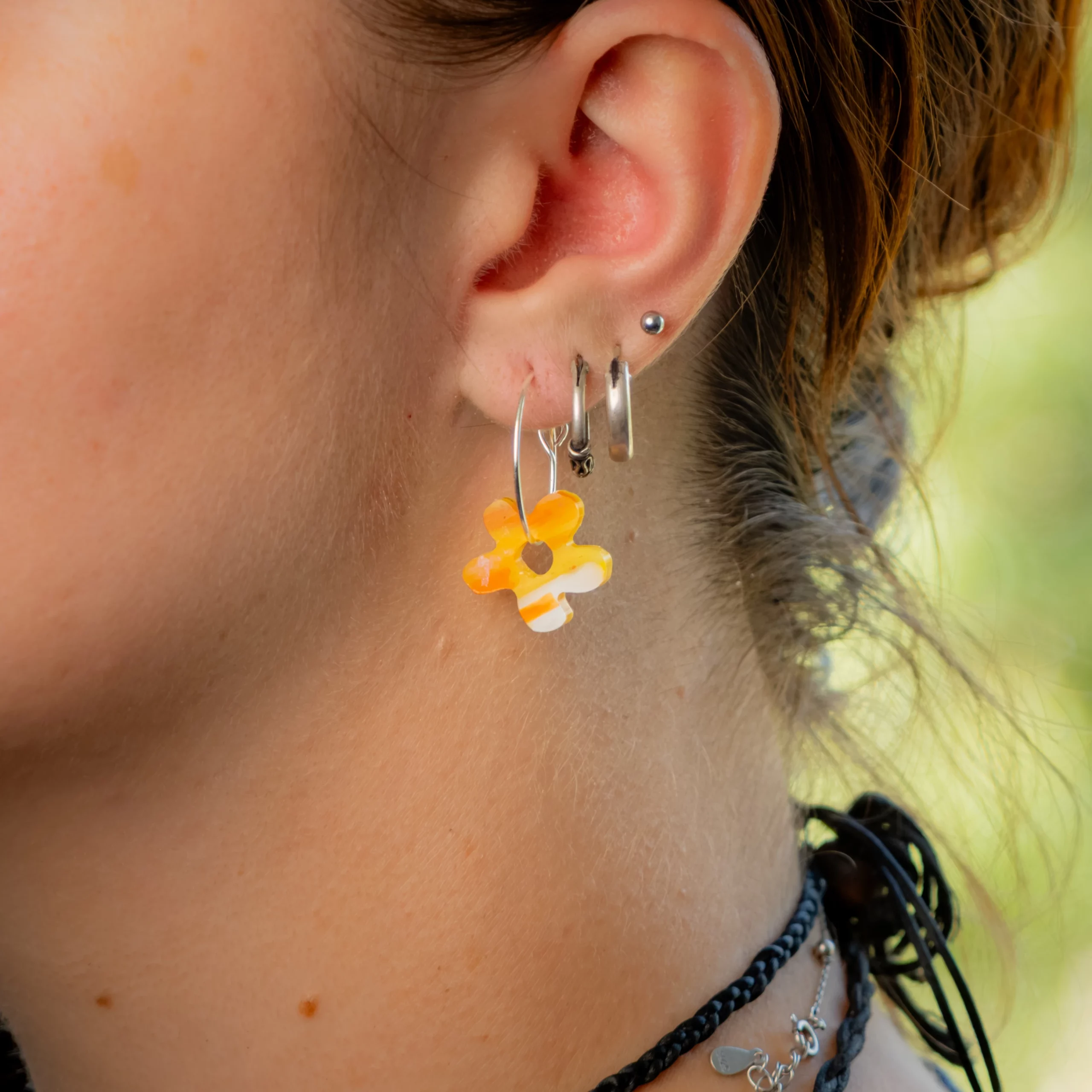 Femme portant la boucle d'oreille recyclée Fleur de Sauvage Méditerranée, collection Les Beaux Jours, coloris Jaune Orange Blanc.