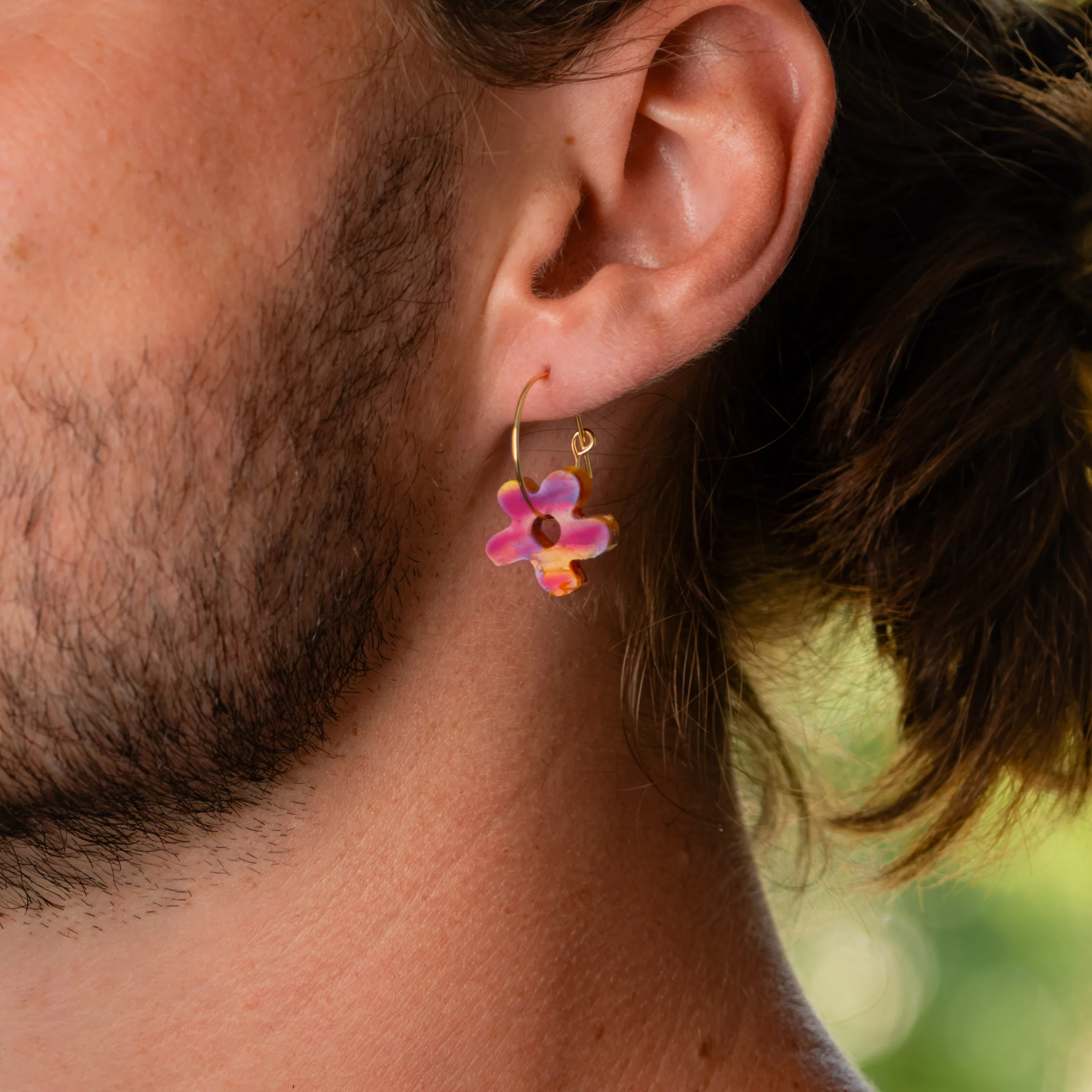 Homme portant la boucle d'oreille recyclée Fleur de Sauvage Méditerranée, collection Les Beaux Jours, coloris Violet/Rose Jaune Orange.