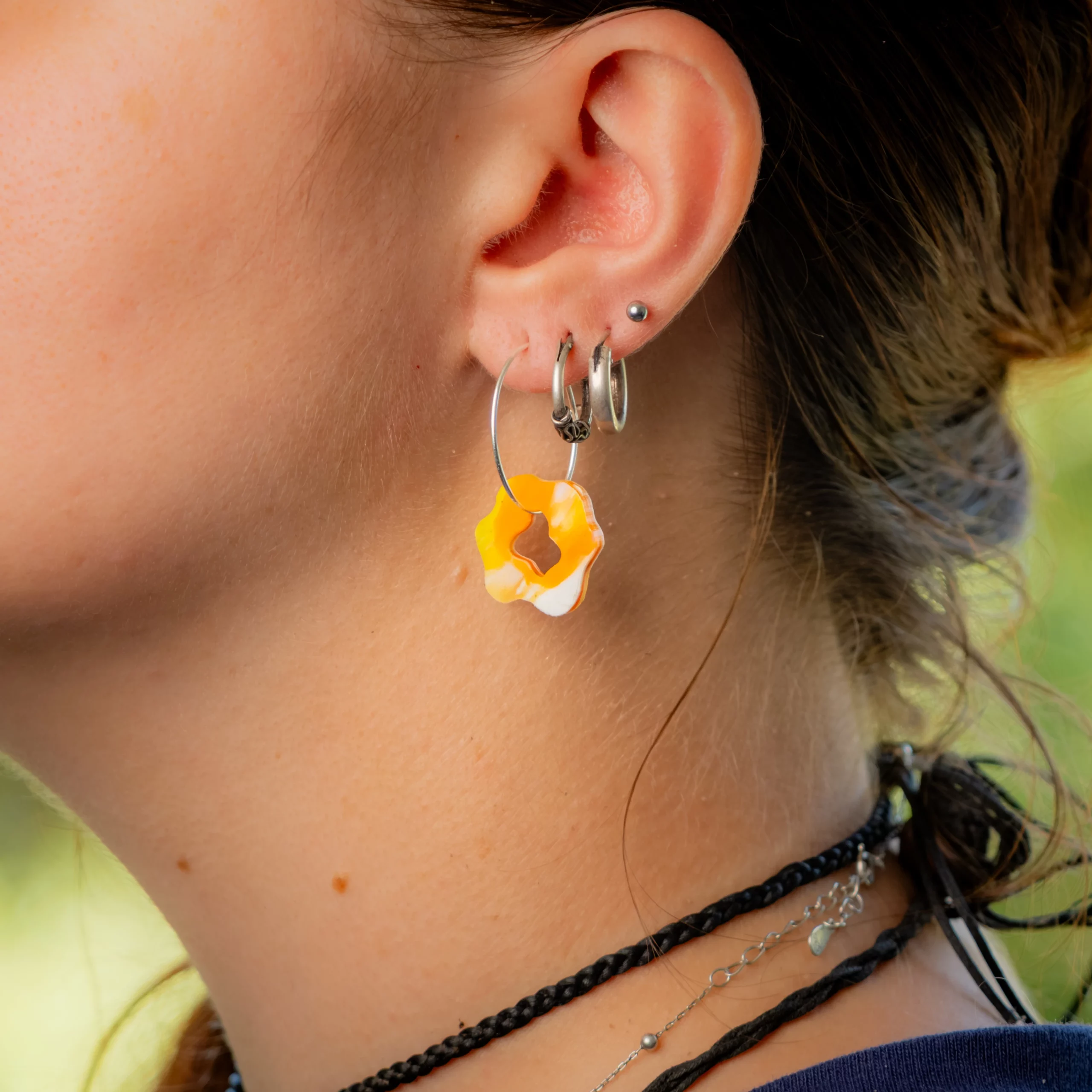 Femme portant la boucle d'oreille recyclée Pétale de Sauvage Méditerranée, collection Les Beaux Jours, coloris Jaune Orange Blanc.