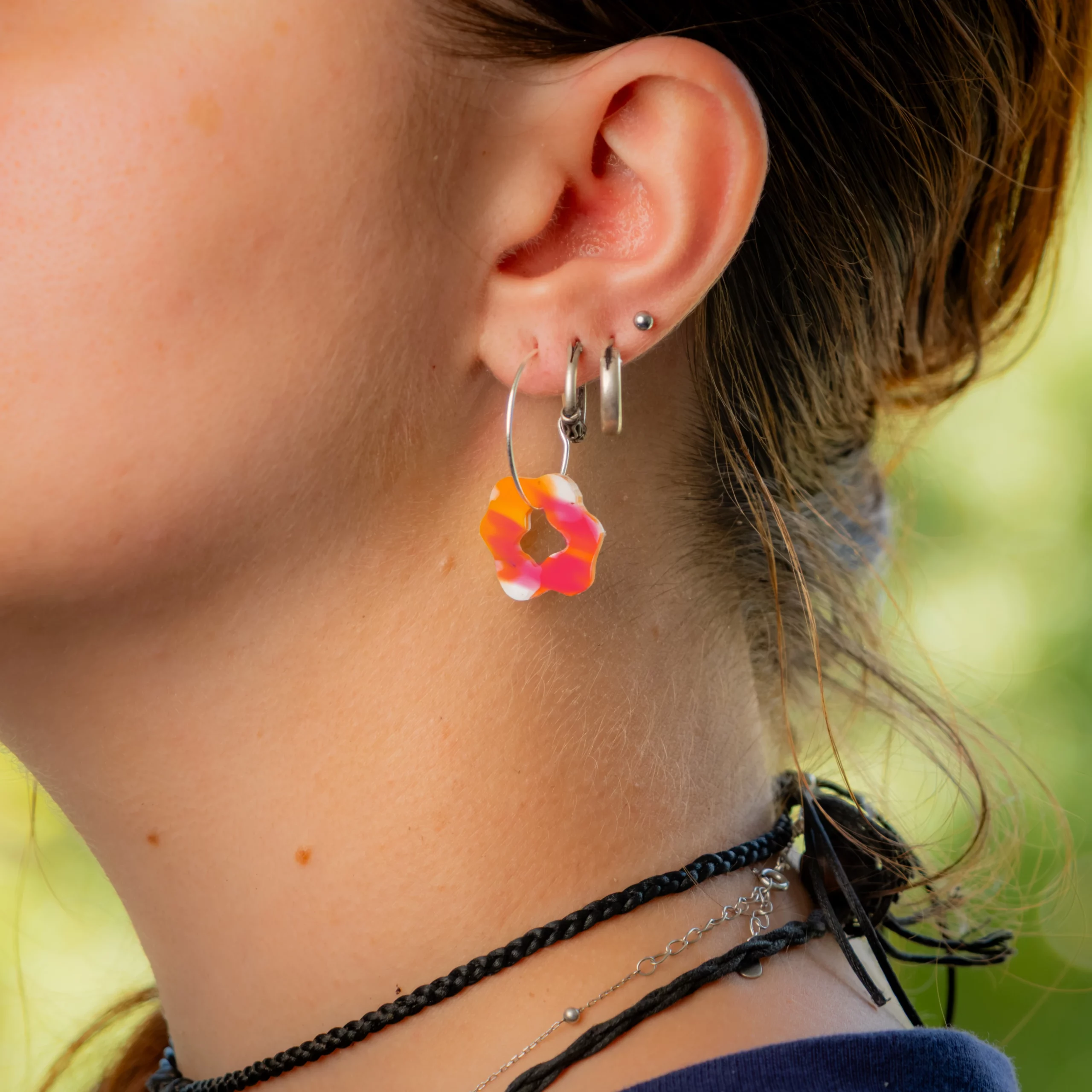Femme portant la boucle d'oreille recyclée Pétale de Sauvage Méditerranée, collection Les Beaux Jours, coloris Violet/Rose Jaune Orange.